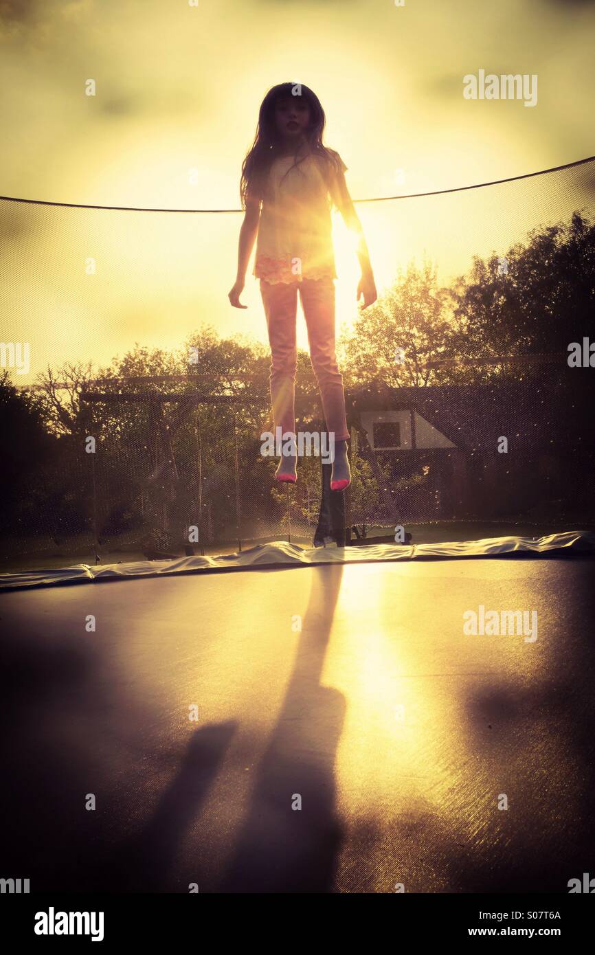 Starten. Ein junges Mädchen, das Hüpfen auf einem Garten Trampolin - Lift off-Alltag ungerade Stockfoto