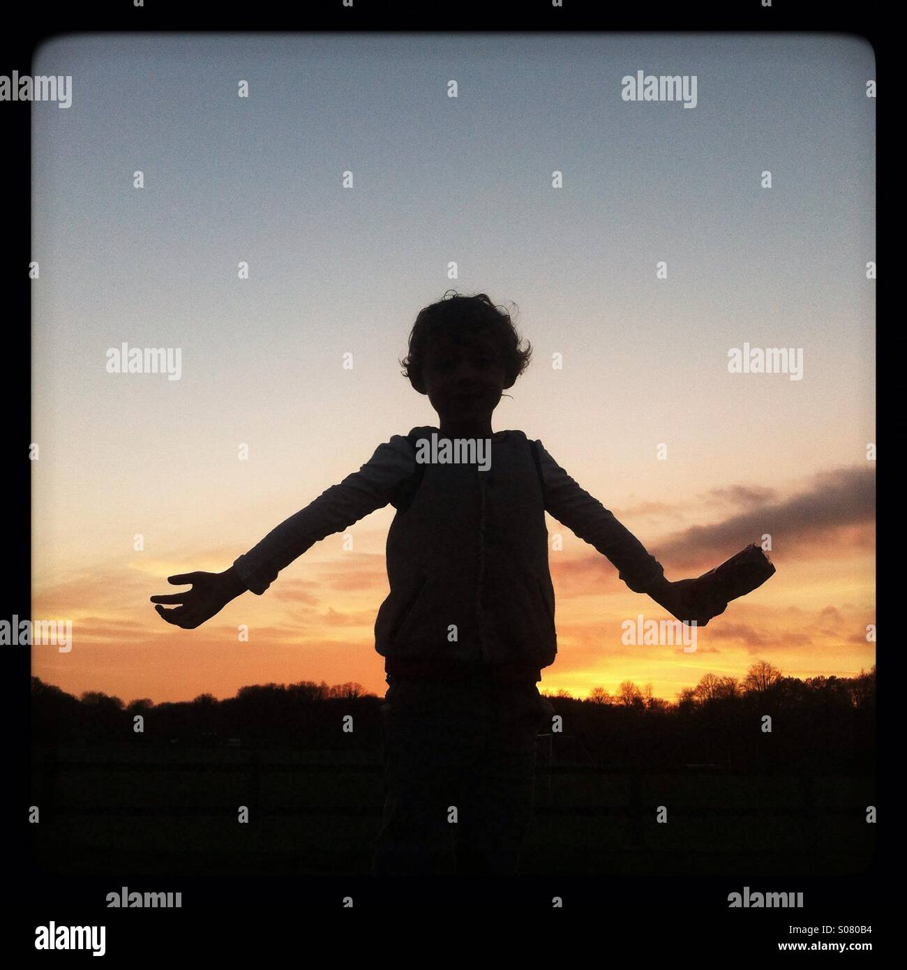 Silhouette eines jungen vor einem Sonnenuntergang, Hampshire, England, Vereinigtes Königreich. - Smartphone-aufgenommenes Stockfoto
