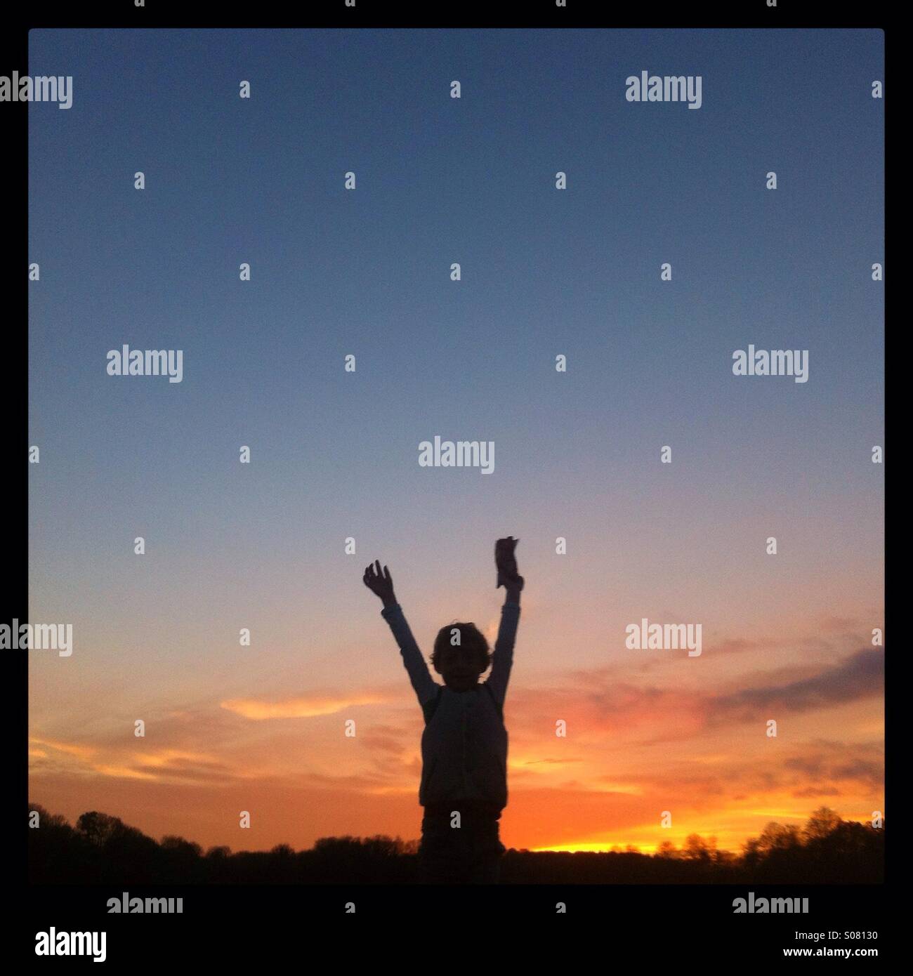 Fünf Jahre alter Junge Silhouette gegen einen Winter Sonnenuntergang - Smartphone-aufgenommenes Stockfoto