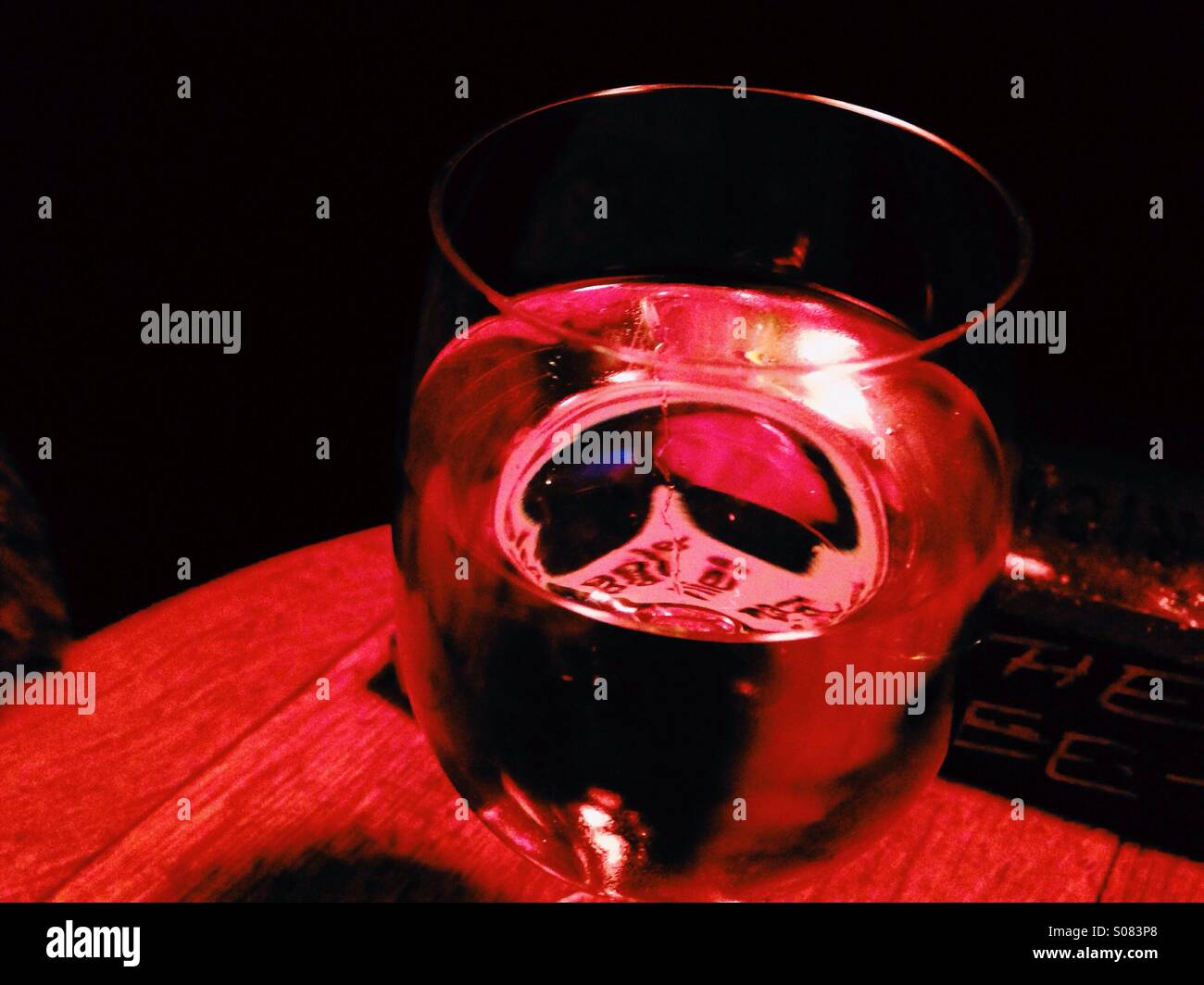 Überlegungen zu einem Glas Wein unter Rotlicht Stockfoto