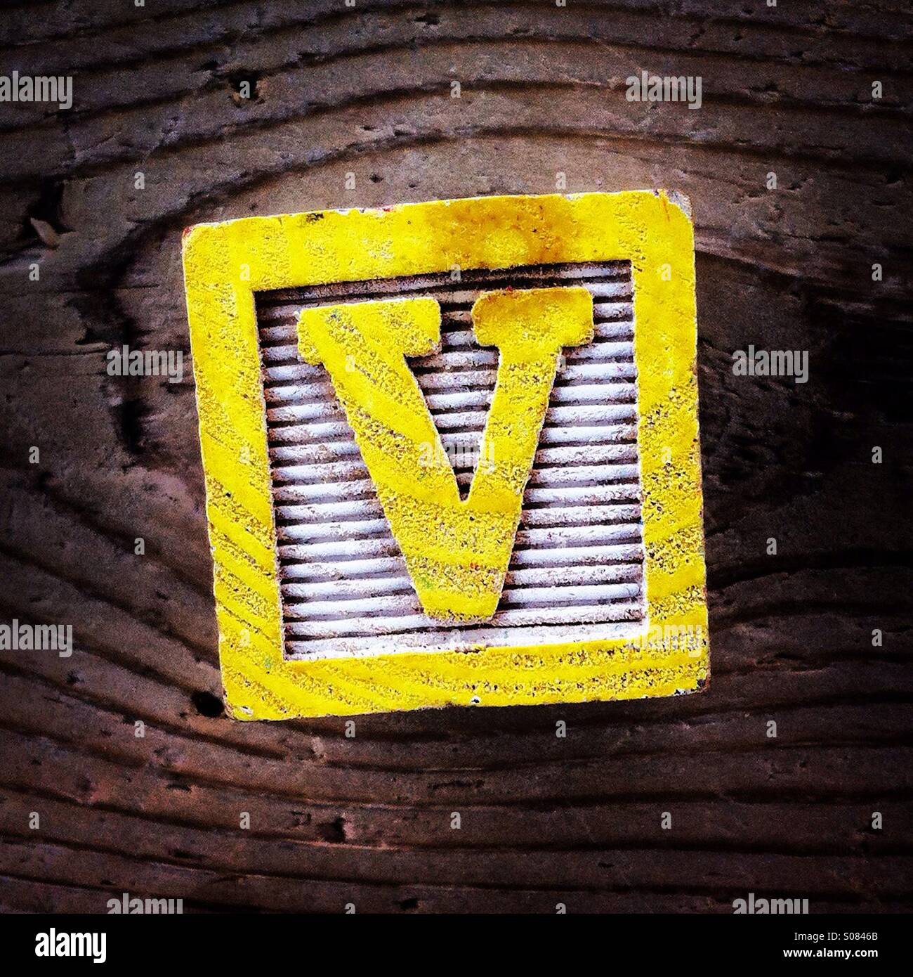 Buchstabe V auf eine Holz-block - Smartphone-aufgenommenes Stockfoto