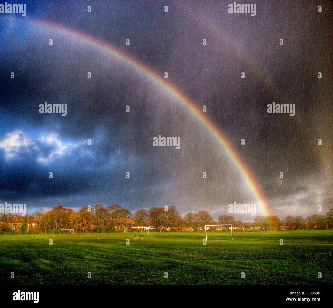 Regenbogen und Regen über Fußballplatz Stockfoto
