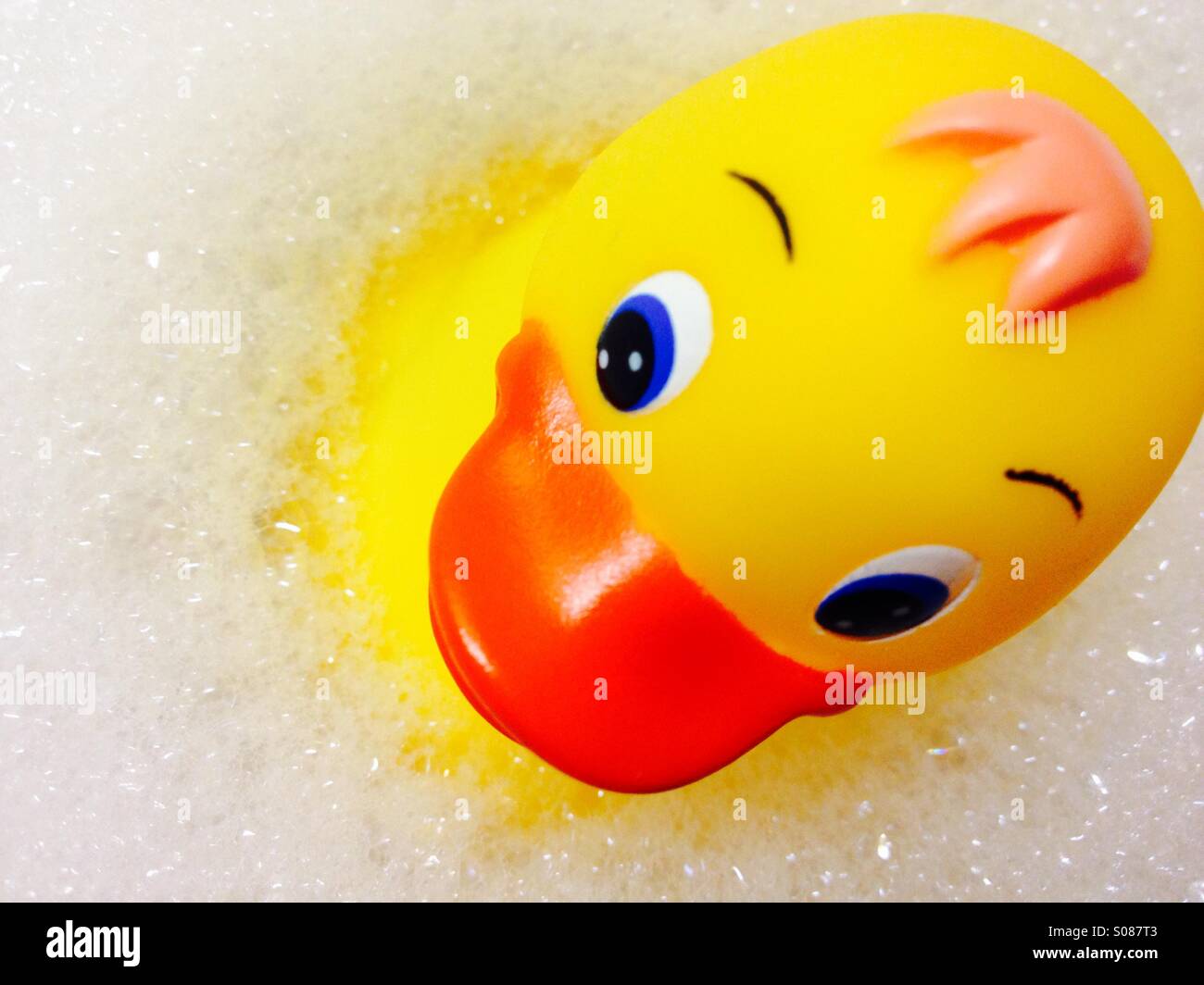 Bild einer gelben Kunststoff Ente schwimmend auf schaumigen Bläschen Stockfoto