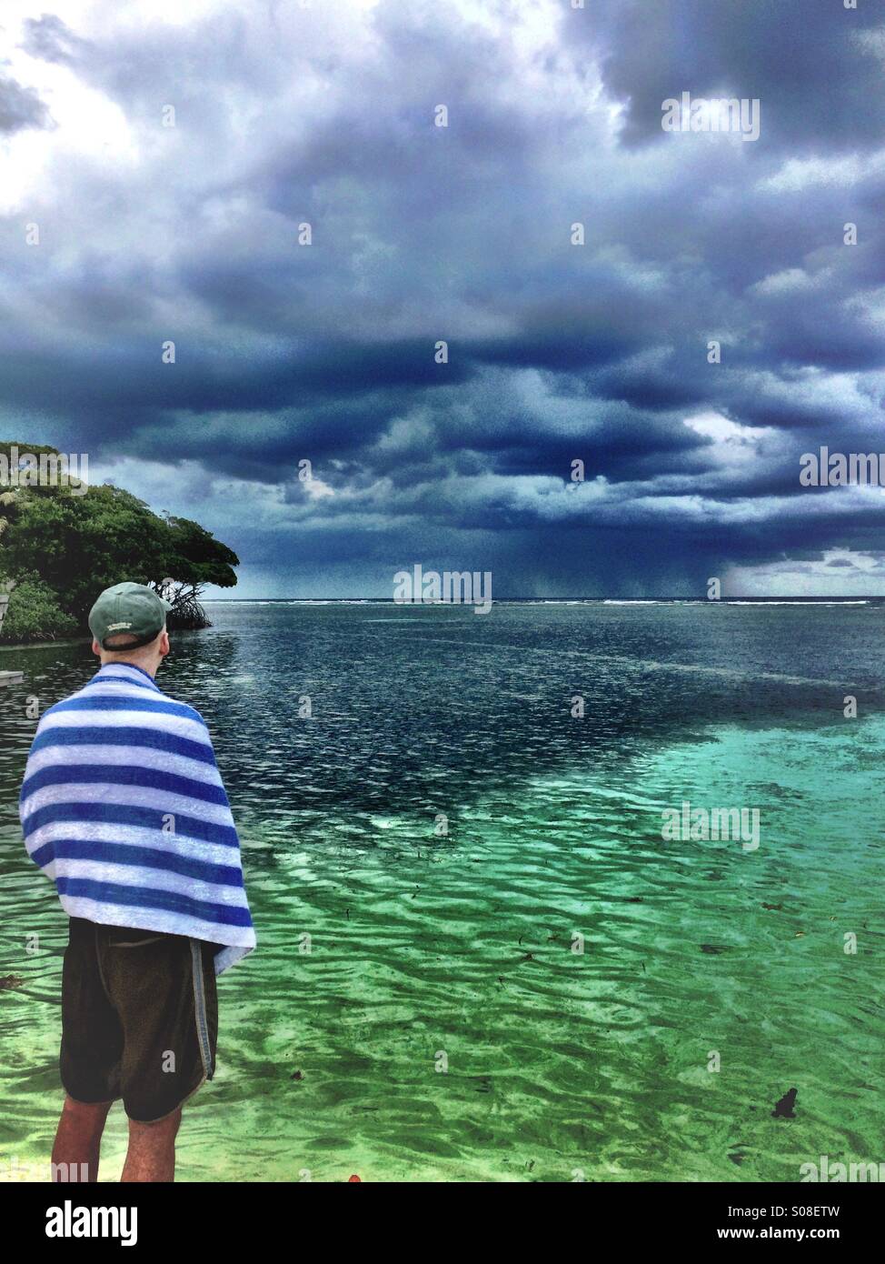 Mann beobachtet Sturm am Strand im Urlaub, Belize und Karibik Stockfoto