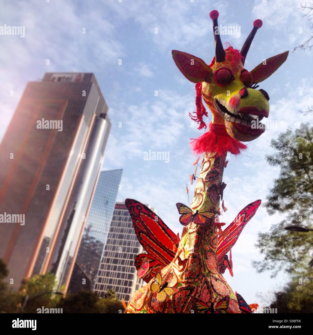 riesige Papier Papiermache Skulptur eine geflügelte Giraffe und einem Wolkenkratzer in der Alebrijes Monumentales Parade, Reforma Ave, Mexico City, Mexiko. Kunstwerk namens Girabrije Künstlers Enrique Luis Estrada Alfaro - Smartphone-aufgenommenes Stockfoto