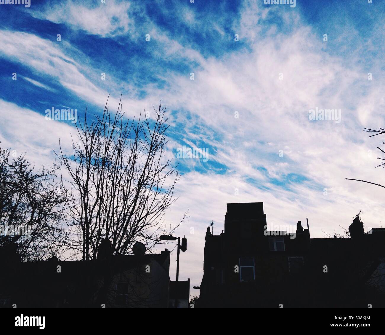 Silhouette Häuser und Bäume vor blauem Himmel mit Wolken gestreift Stockfoto