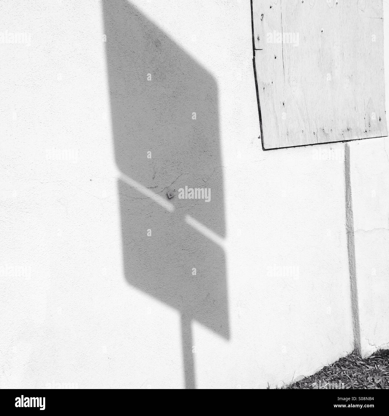 Straßenschild Schatten auf gepatchte Gebäudewand Stockfoto
