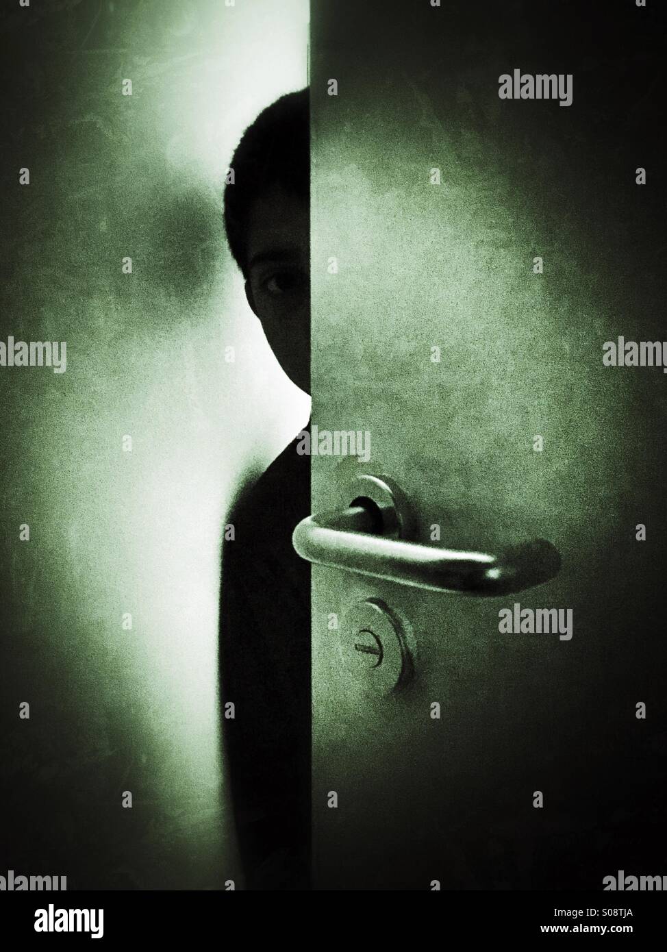 Angst junge versteckt sich hinter Tür Stockfoto