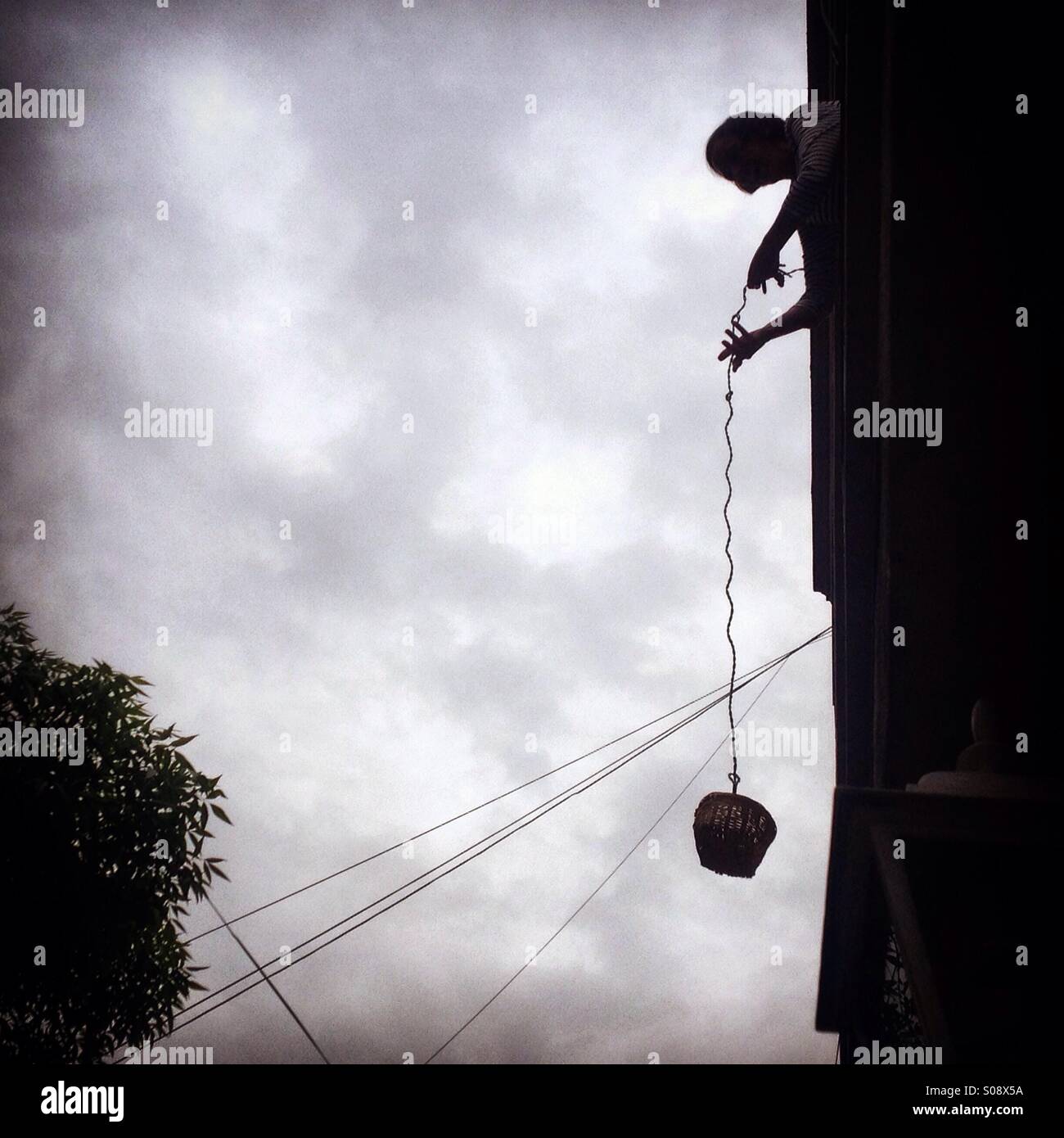 Eine Frau benutzt einen Korb für Schlüsselübergabe in einem Haus Colonia Roma, Mexiko-Stadt, Mexiko - Smartphone-aufgenommenes Stockfoto