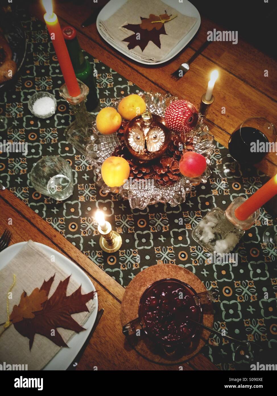 Weihnachtstisch mit Ornamenten, Tannenzapfen, Obst, Eichenlaub und Kerzen dekoriert. - Smartphone-aufgenommenes Stockfoto