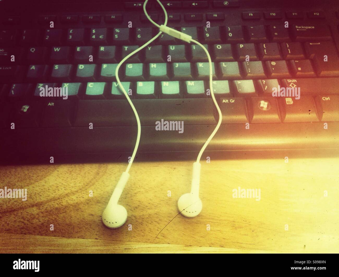 Ohrhörer und Tastatur mit Grunge-Effekt. - Smartphone-aufgenommenes Stockfoto