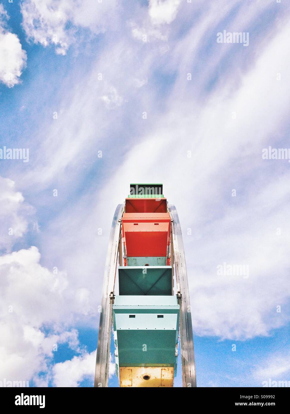 Blickte zu einem bunten Riesenrad im offenen blauen Himmel mit Wolken. Stockfoto