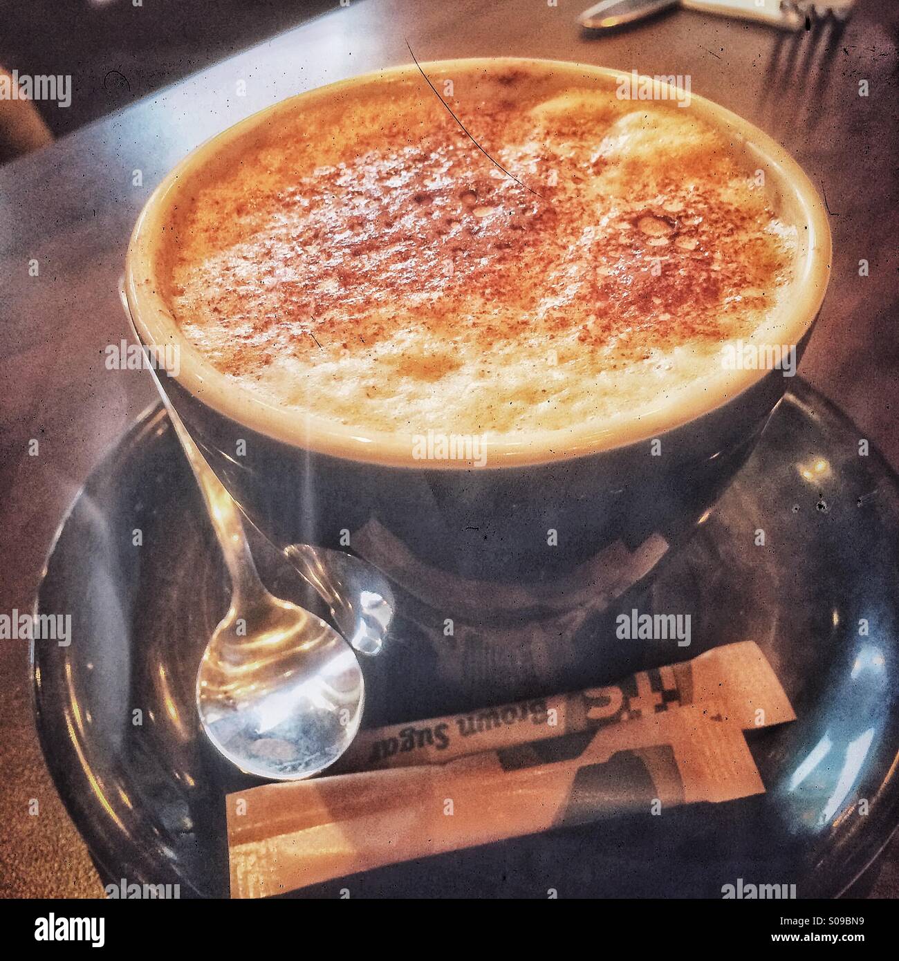 Eine Tasse Cappuccino mit einer Bedeckung von Schokolade abstauben. Stockfoto