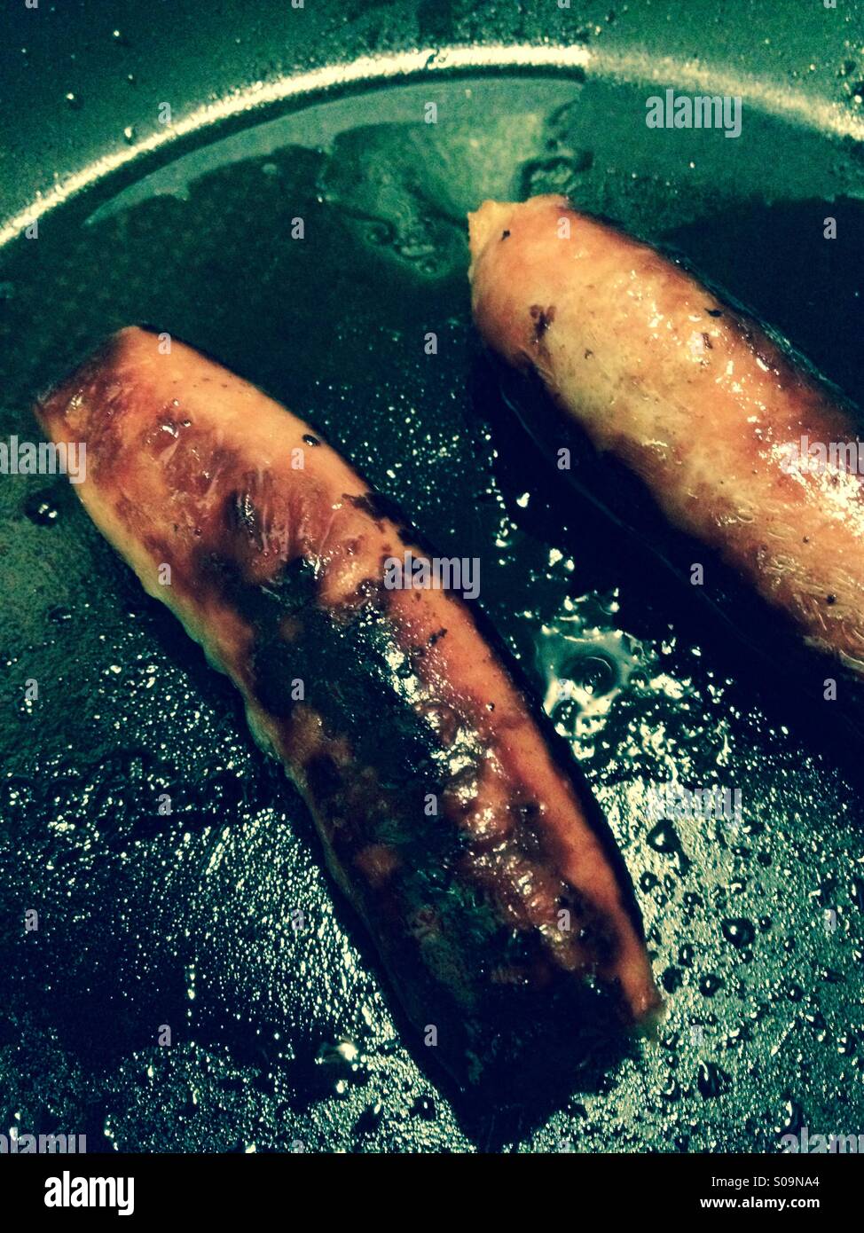 Zwei Würstchen aus Schweinefleisch in einer Pfanne erhitzen Stockfoto