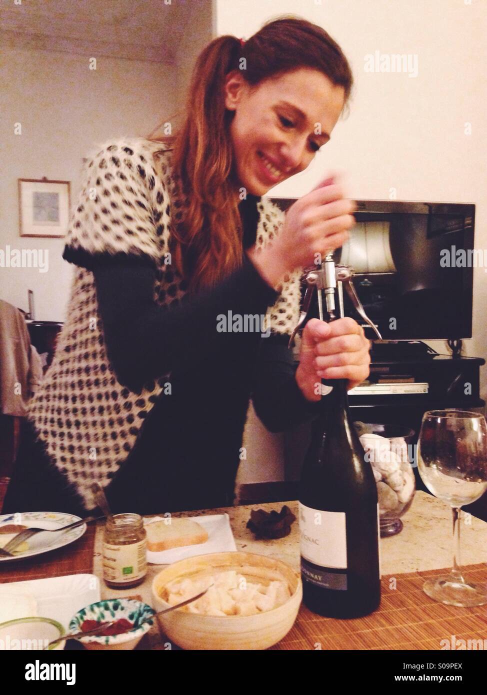 Junge Frau, eine Flasche Wein öffnen Stockfoto