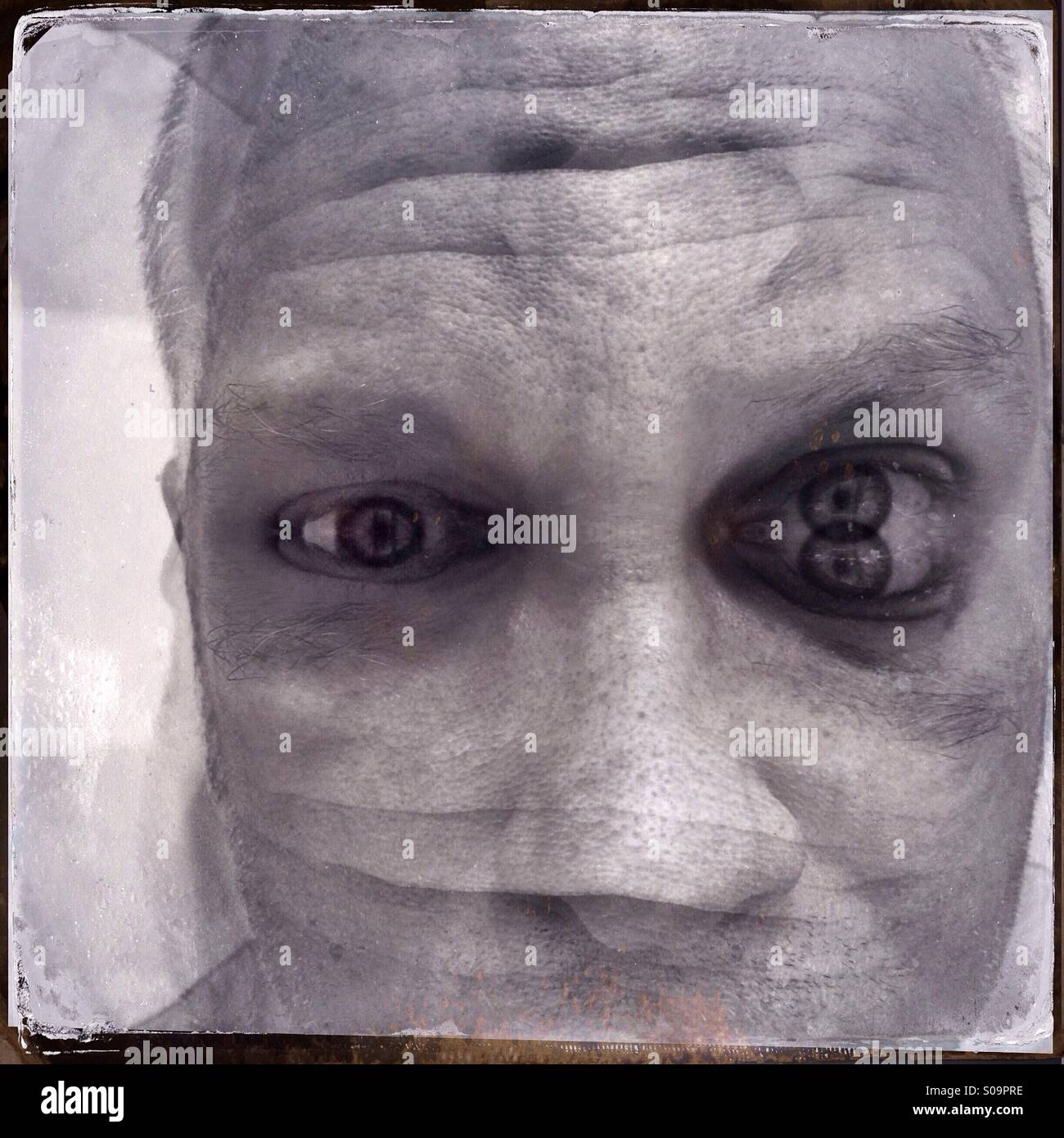 Surreal schwarz / weiss Portrait eines Mannes, doppelte ausgesetzt und reflektiert, so dass seine Gesichtszüge verzerrt sind. Stockfoto