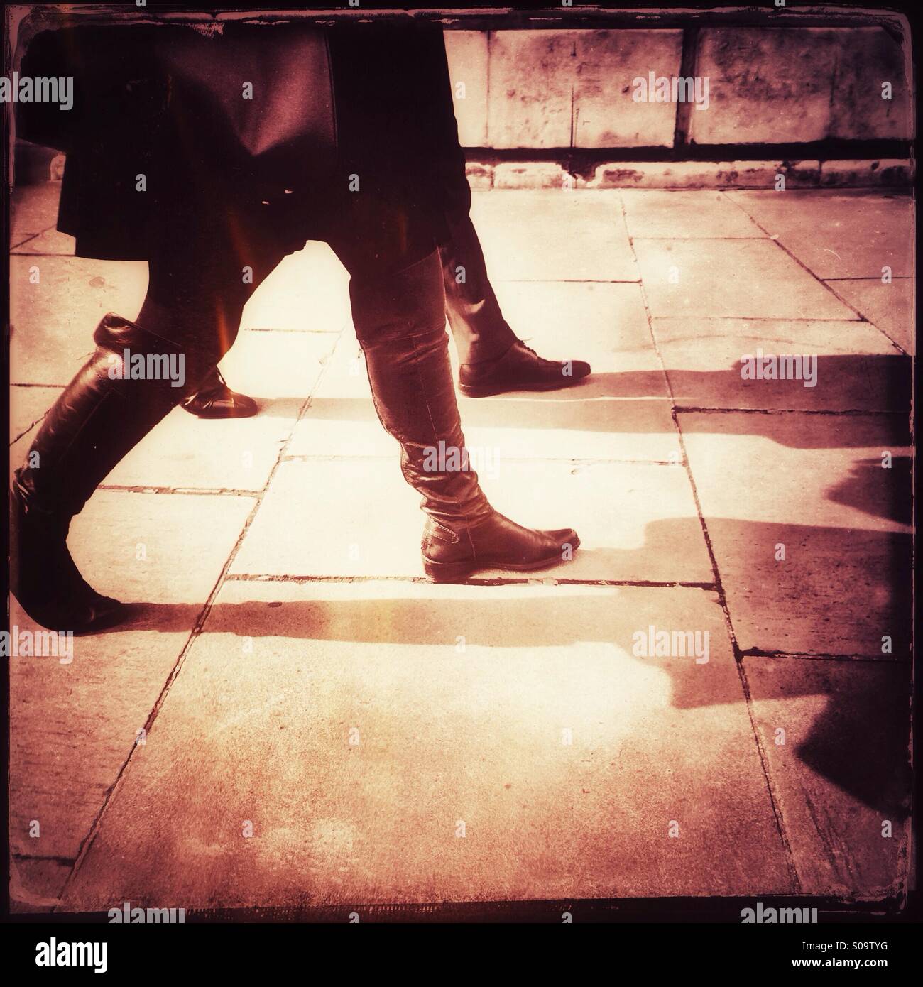 Rot getönten Foto von zwei Menschen zu Fuß und werfen Schatten auf den Bürgersteig. Stockfoto