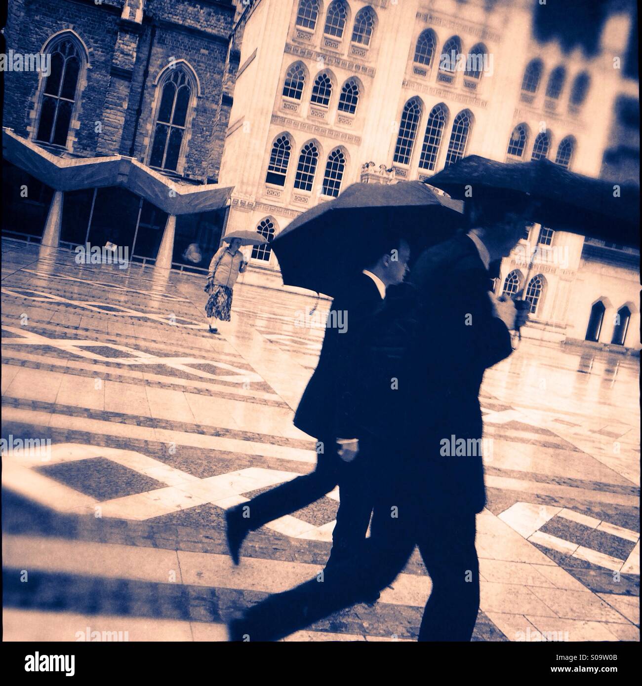 Menschen, die Schirme zu Fuß über den Regen getränkt Hof der Londoner Guildhall, England, UK. Stockfoto