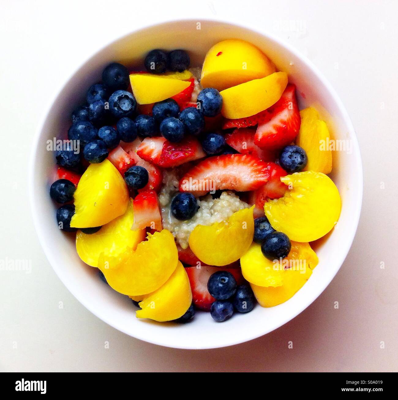 Sommerliche Haferflocken bedeckt mit bunten Früchten und Beeren Stockfoto