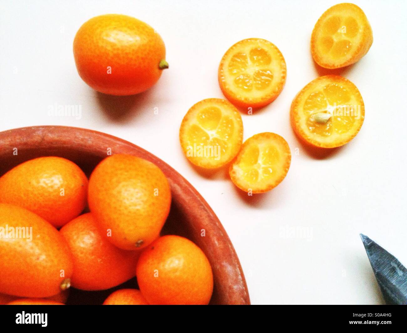In Scheiben geschnittene orange Kumquats auf eine Arbeitsplatte Stockfoto