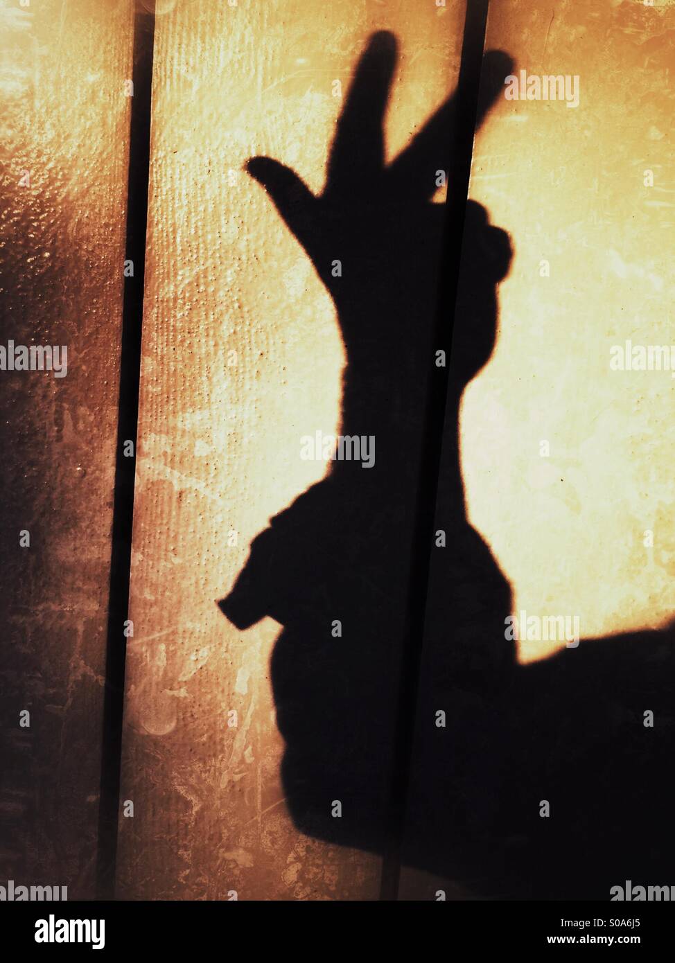 Ein Mann wirft einen Schatten auf die Wand auf seiner Hand zählen. Nummer drei. Stockfoto
