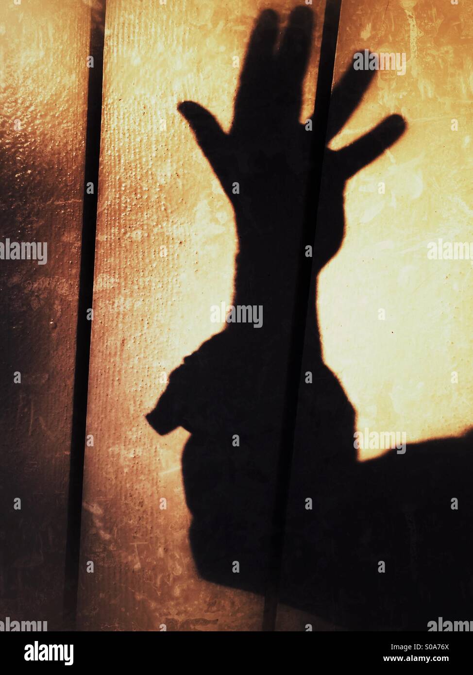 Ein Mann wirft einen Schatten auf die Wand auf seiner Hand zählen. Nummer fünf. Stockfoto