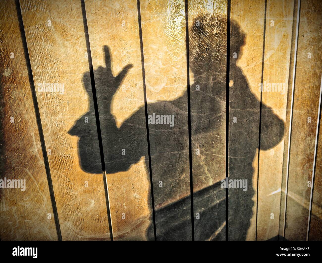 Ein Mann wirft einen Schatten auf die Wand auf seiner Hand zählen. Nummer zwei. Stockfoto