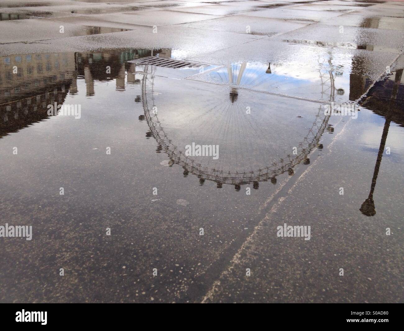 Das London Eye, gefangen in der Reflexion einer Pfütze an einem regnerischen Tag in London Stockfoto