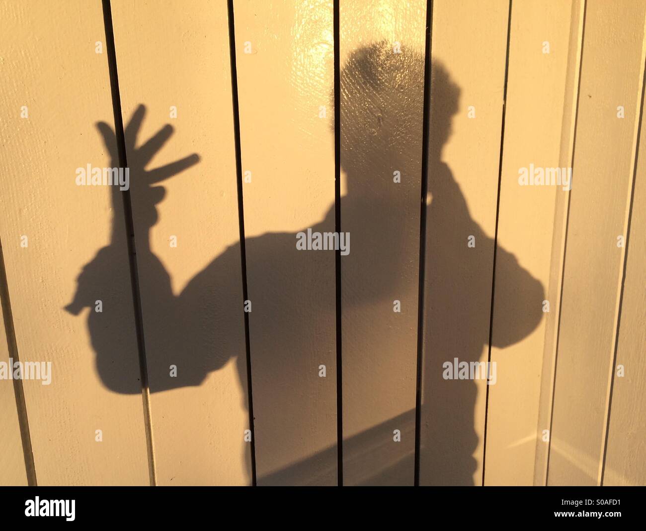 Ein Mann wirft einen Schatten an der Wand, an den Fingern seiner Hand zählen. Nummer vier. Stockfoto