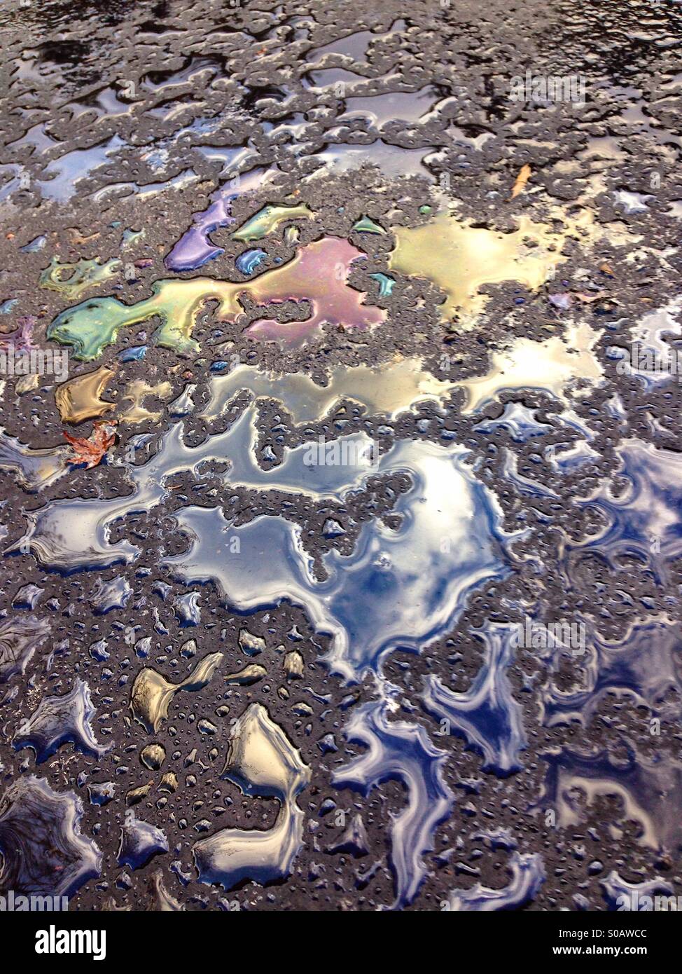 Regenwasser und Öl bilden Farben auf Bürgersteig - Smartphone-aufgenommenes Stockfoto