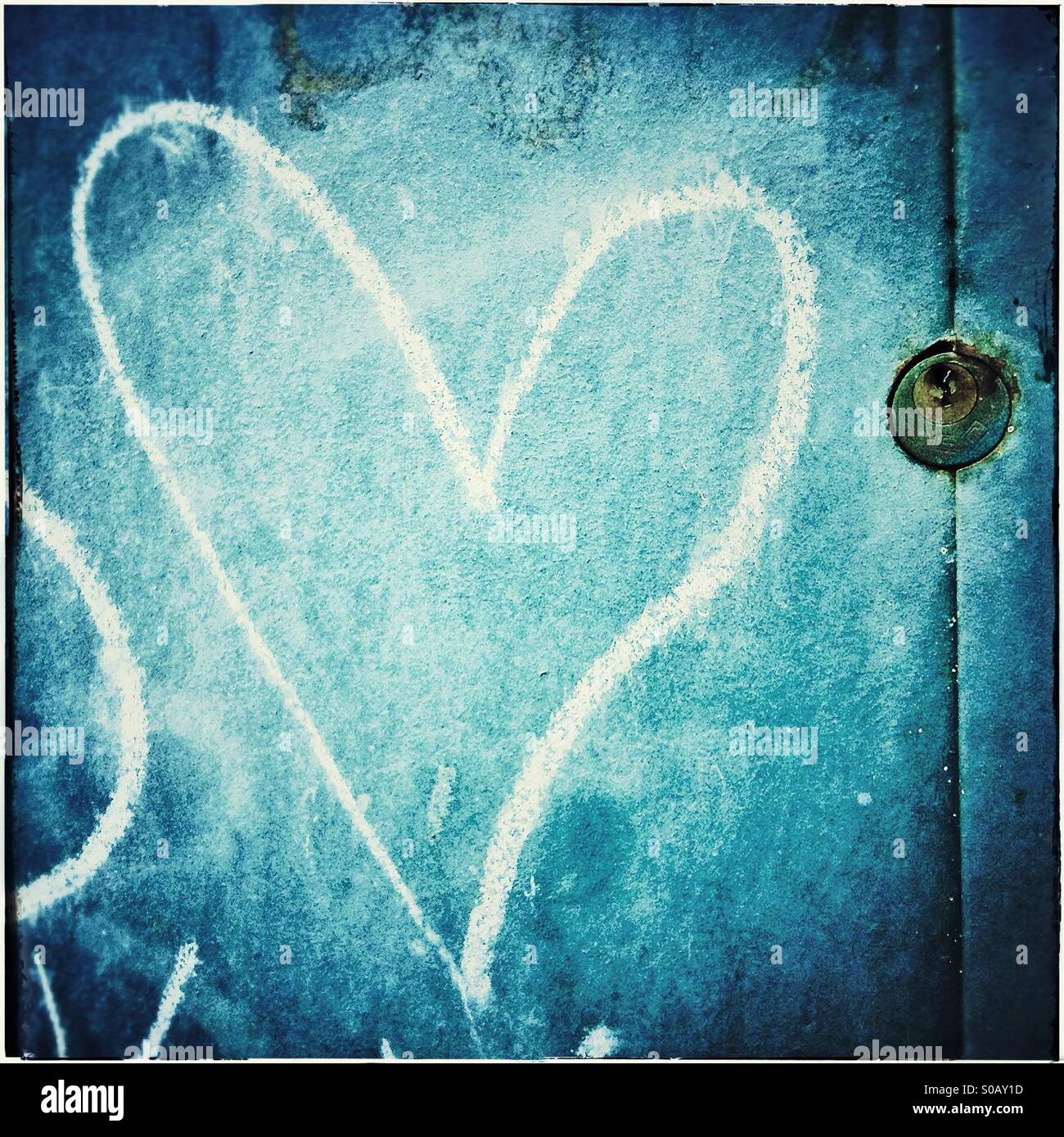 Ein Herz gemalt in Kreide und ein Vorhängeschloss in einer blauen Tür Stockfoto
