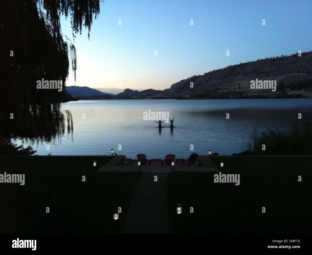 Späten Sommerabend am See mit 2 Männern Silhouette im See mit den Armen weit gedehnt. Stockfoto