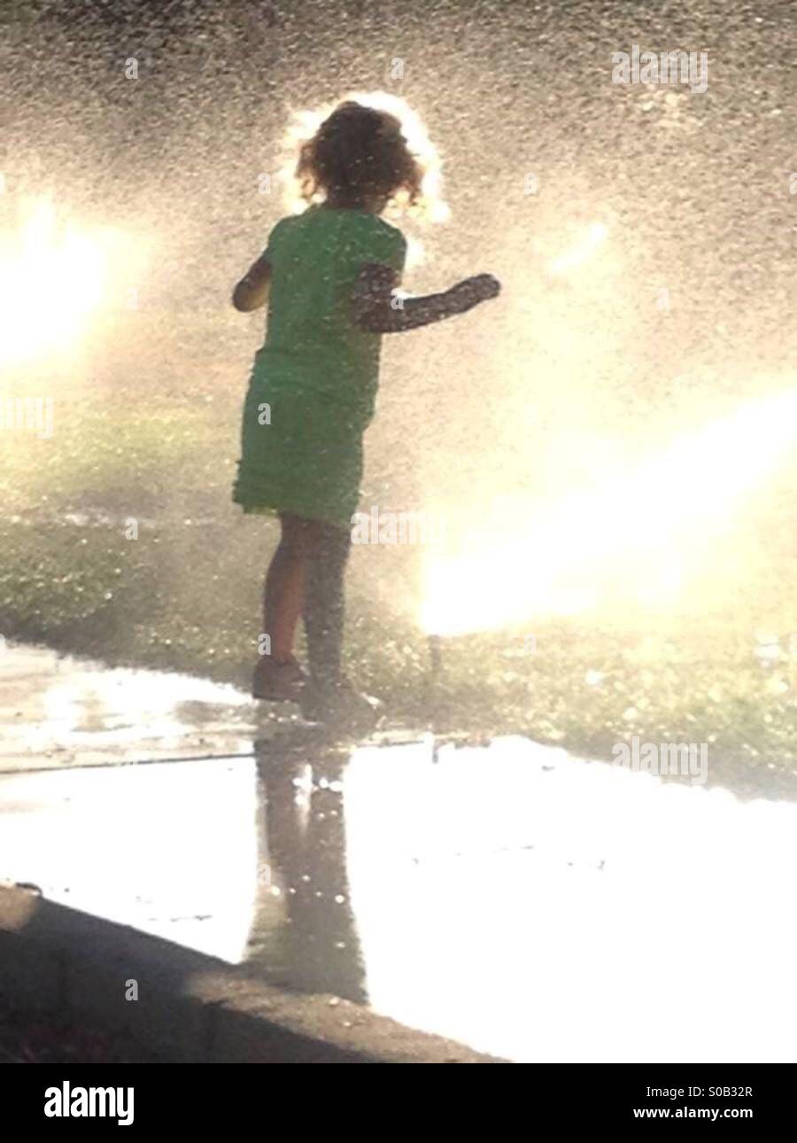 Kleine Mädchen spielen in Sprinkler Stockfoto