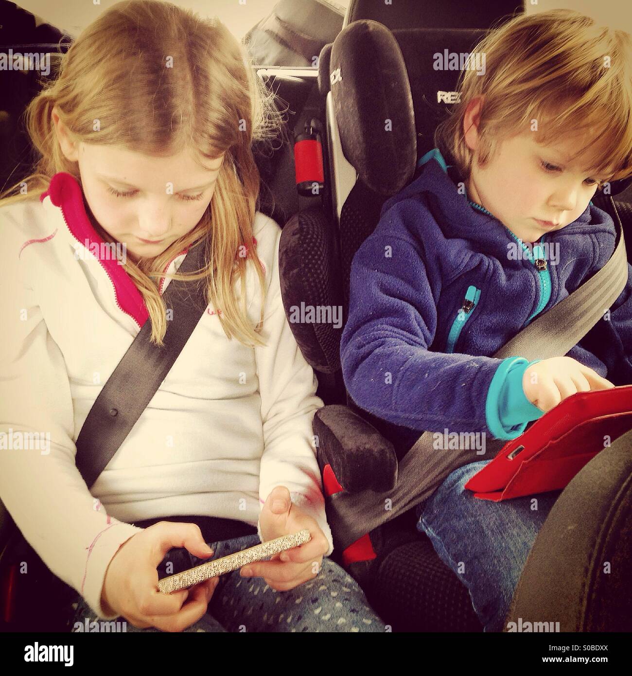 Kinder spielen auf Bildschirmen in einem Auto Stockfoto