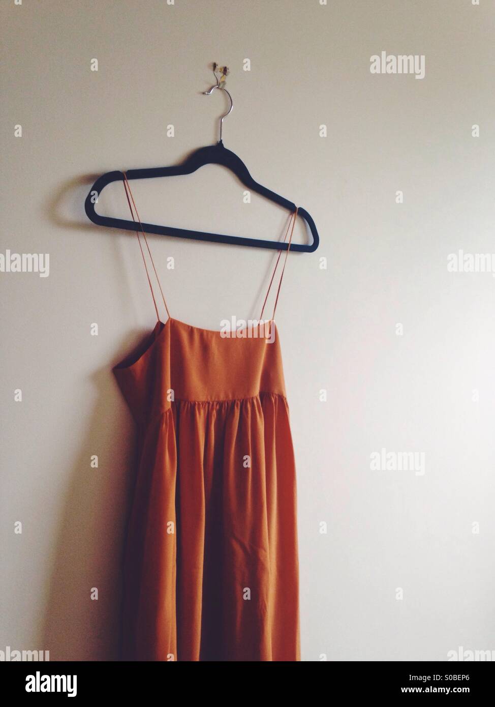 Orange Seidenkleid von einem Kleiderbügel hängen Stockfoto