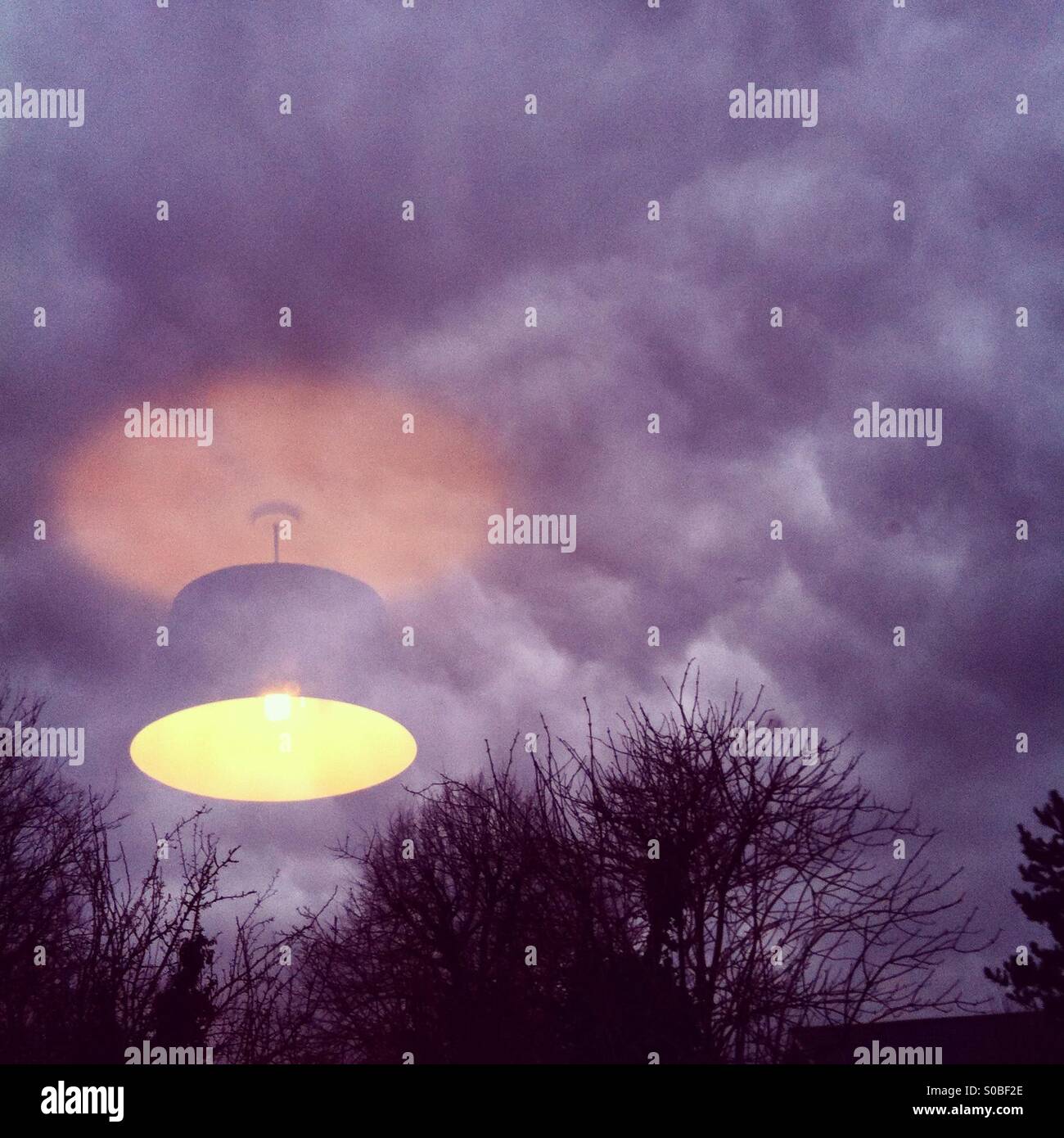 Reflexion von einem Lampenschirm in einem Fenster mit Blick auf ein bewölkter Himmel in der Abenddämmerung Stockfoto