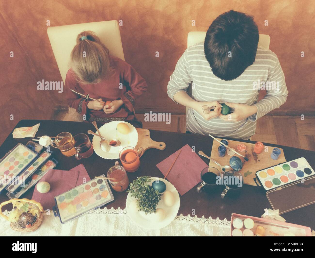 Bruder und Schwester bemalen von Ostereiern zu Hause - Smartphone-aufgenommenes Stockfoto