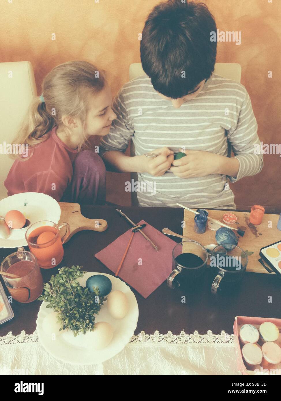 Bruder und Schwester bemalen von Ostereiern zu Hause - Smartphone-aufgenommenes Stockfoto