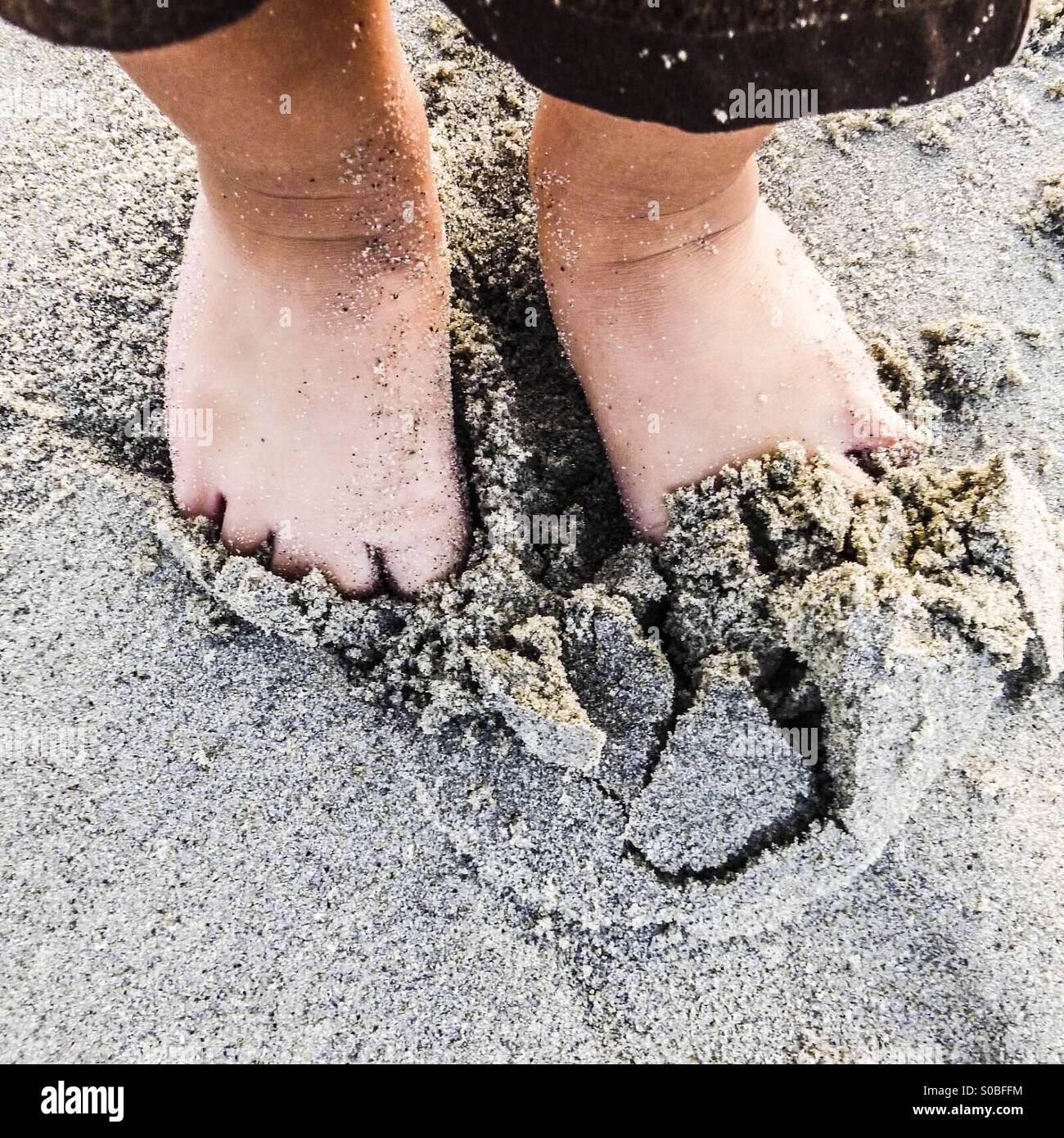Kind, Graben seine Füße in den Sand am Strand Stockfoto