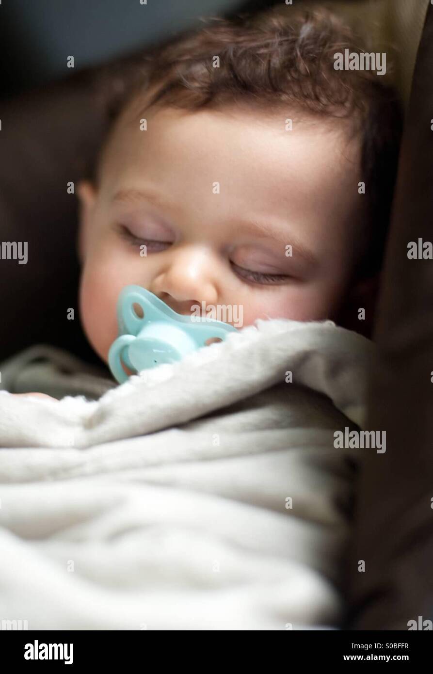 Babyjungen schlafen mit einem Schnuller Stockfoto