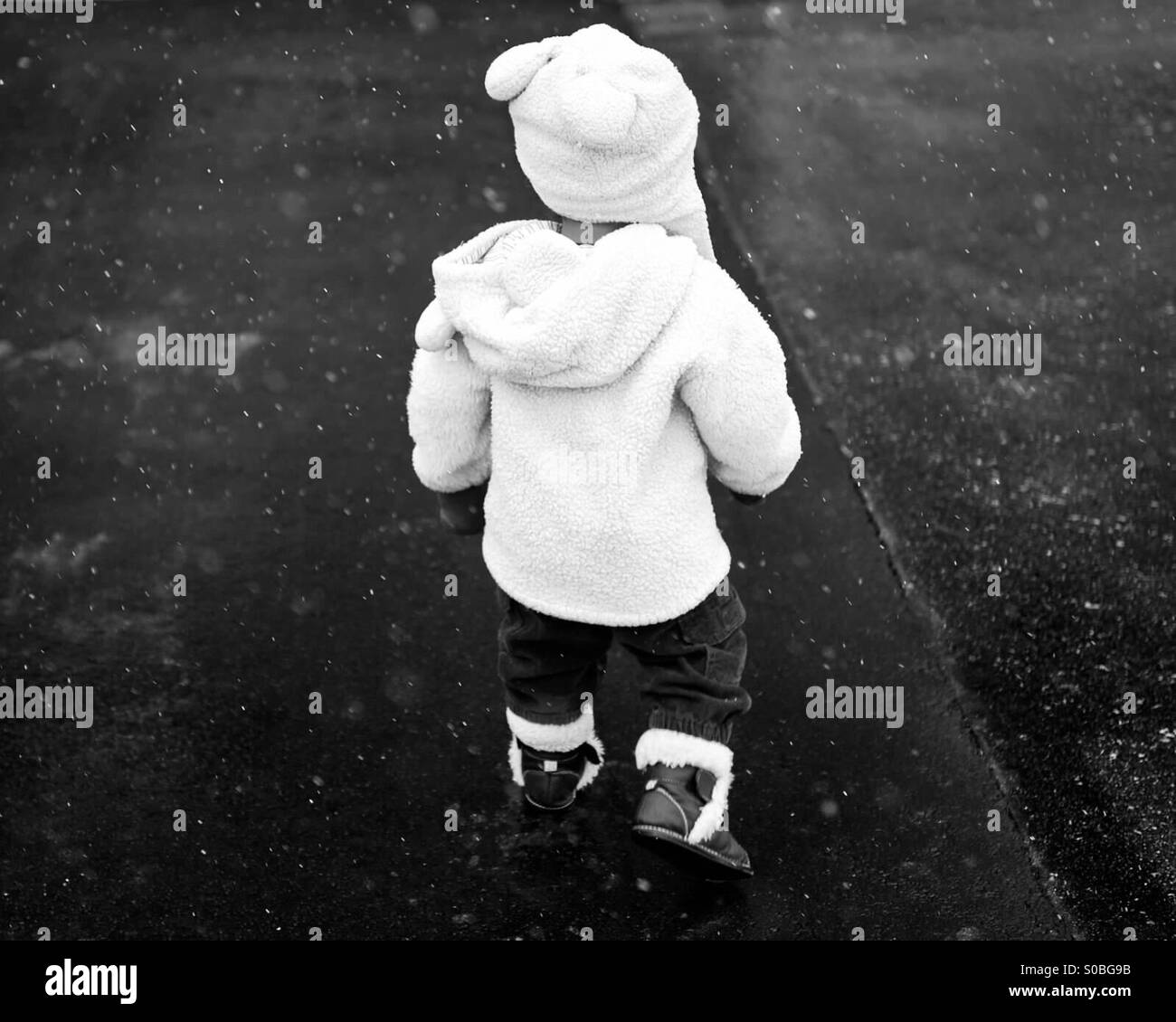Ein Kleinkind zu Fuß in leichter Schneefall Stockfoto