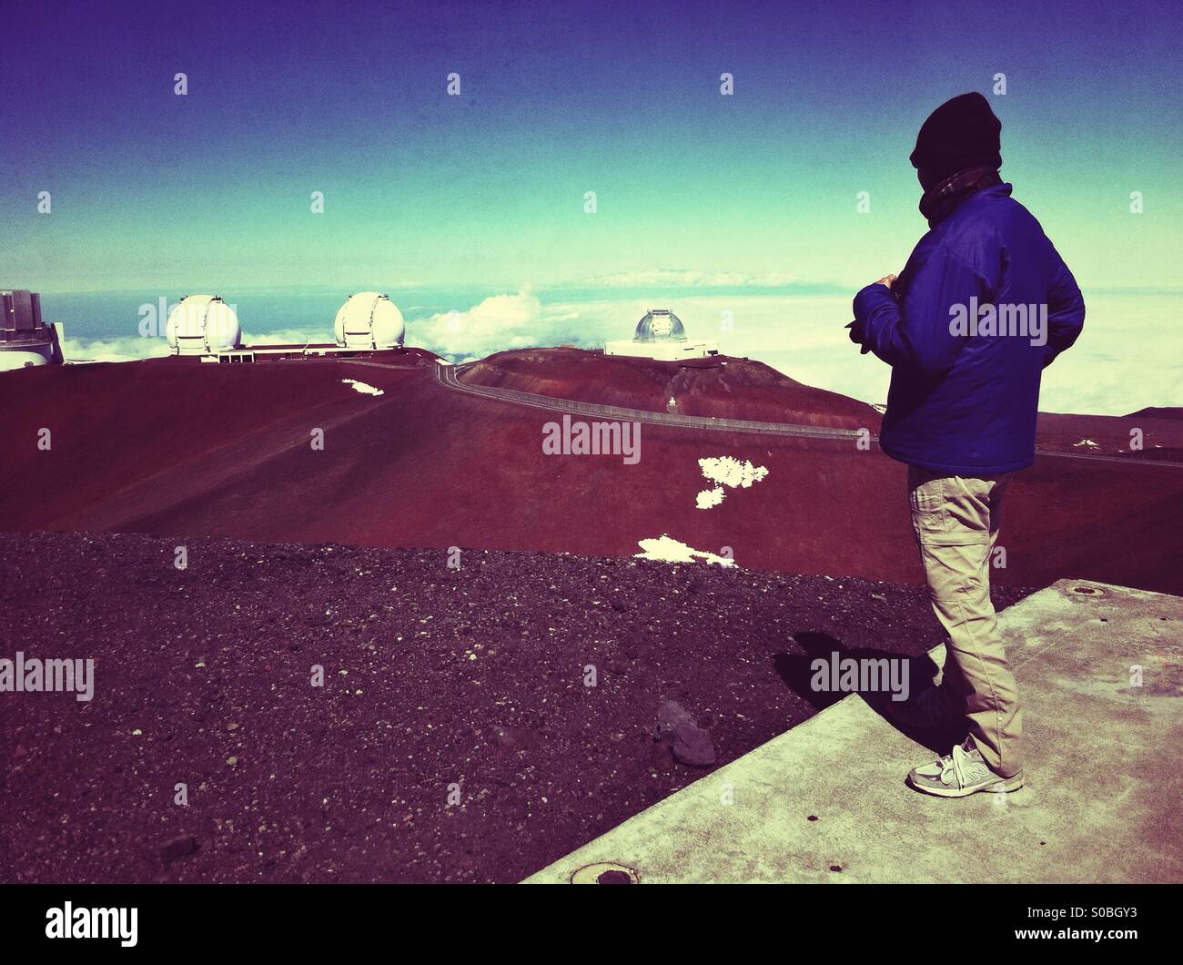 Winterliche gekleideter Mann stand am Anfang von Mauna Kea Vulkan mit Blick auf mehrere RIESENTELESKOPE Stockfoto