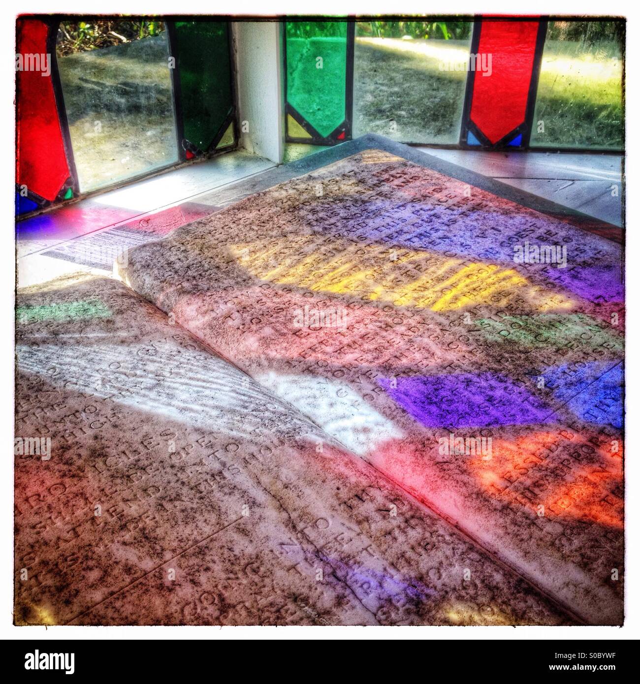 Licht ein Buntglasfenster, die Erstellung von Mustern auf eine geschnitzte Steintafel. Stockfoto