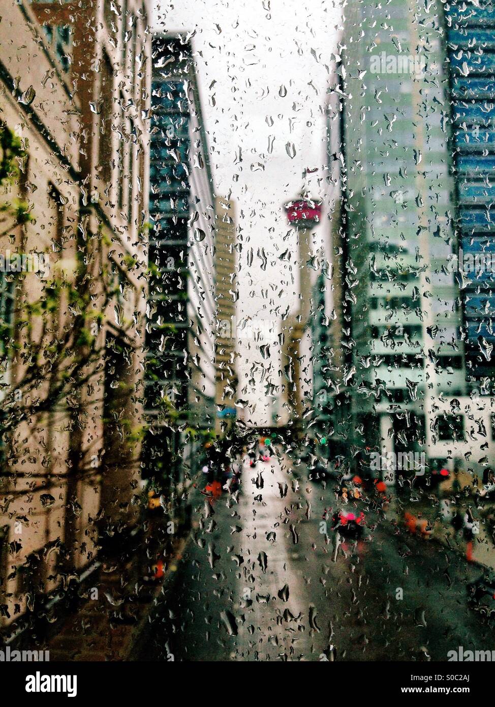 Auf der Suche auf der neunten Avenue durch einen regen bedeckt Fenster in der Innenstadt von Calgary in Richtung der Stadt ikonischen Calgary Tower. Konzentriert sich auf die Regentropfen. Stockfoto