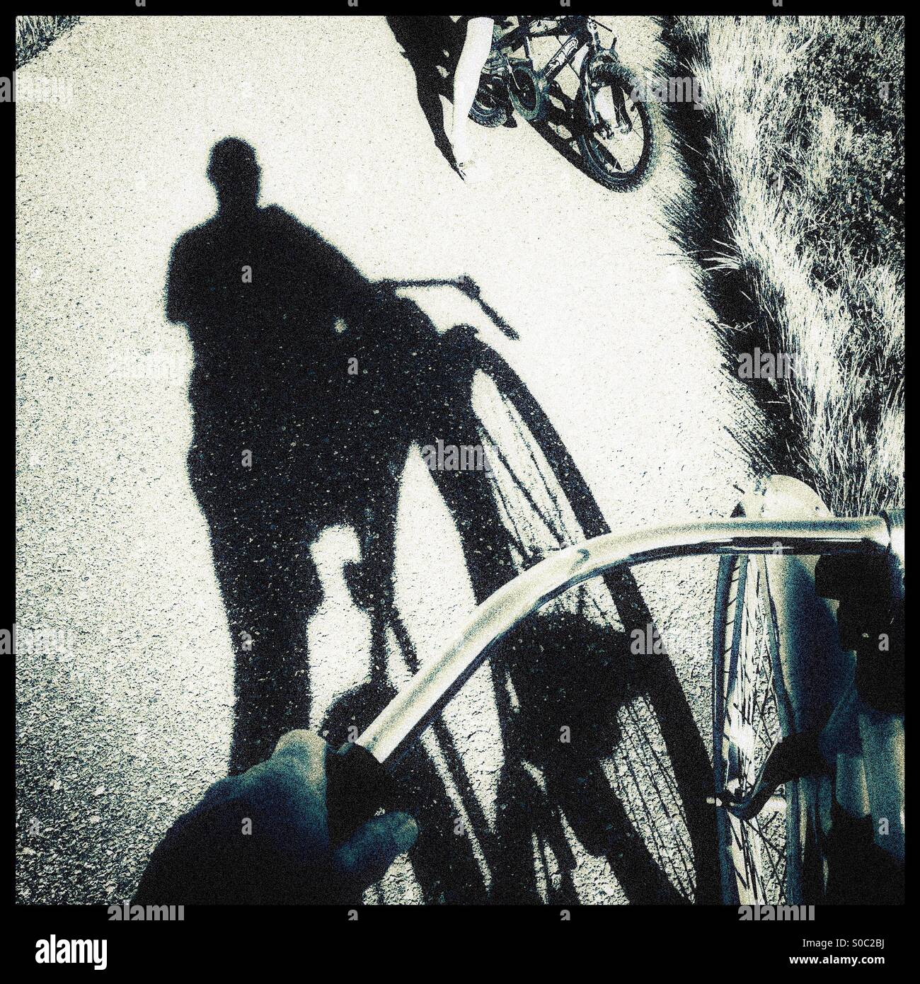 Ein Schatten ein Radfahrer auf einem Radweg im Gespräch mit einem Kind mit dem Fahrrad. Stockfoto