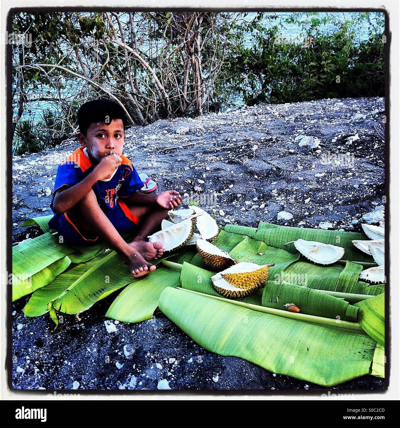 Junge Junge Essen Durian Banane beurlaubt Stockfoto
