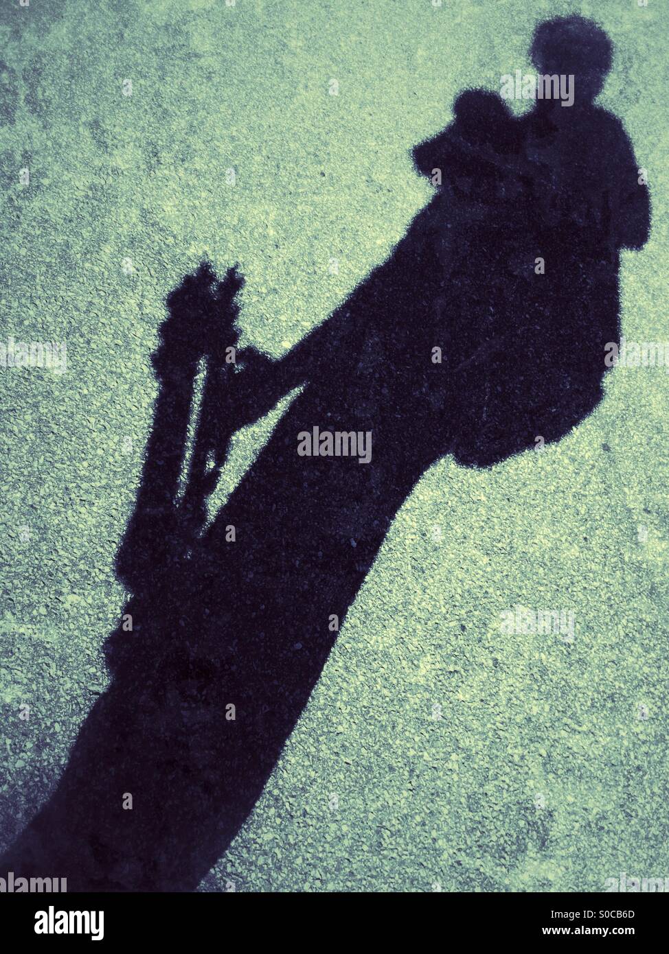 Schatten eines Fotos mit Kamera geschnallt die Brust und Stativ in der Hand. Stockfoto