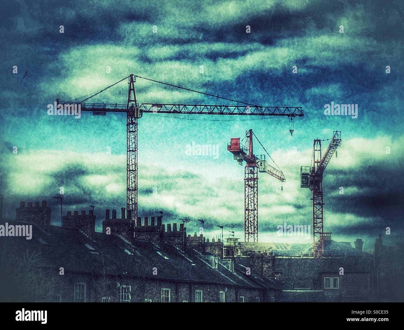 Hohe Baukräne oberhalb einer Wohnsiedlung UK - Smartphone-aufgenommenes Stockfoto