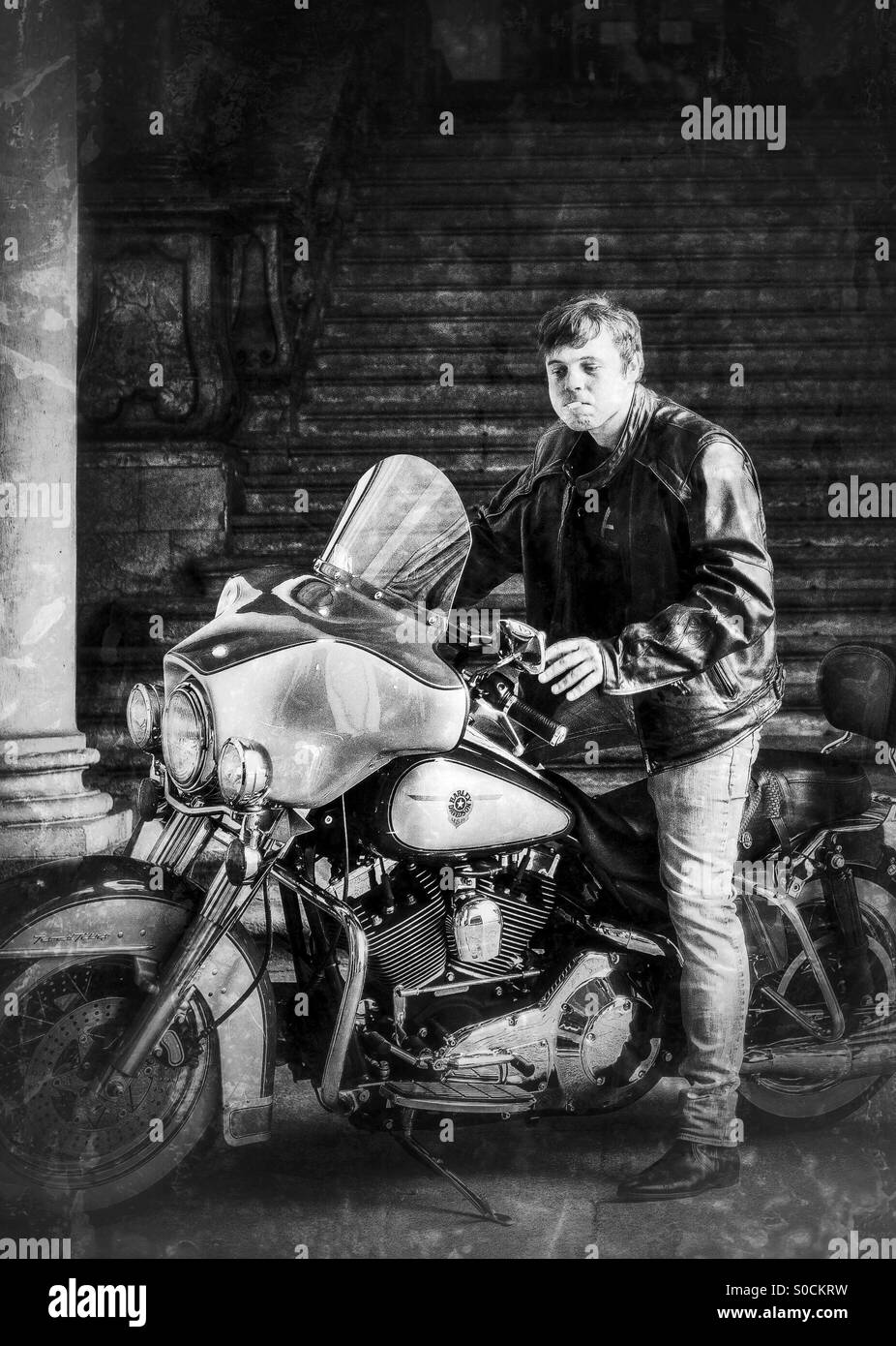 Mann ab einer Harley Davidson beim Rauchen einer Zigarette in einem Rock-Outfit - Smartphone-aufgenommenes Stockfoto
