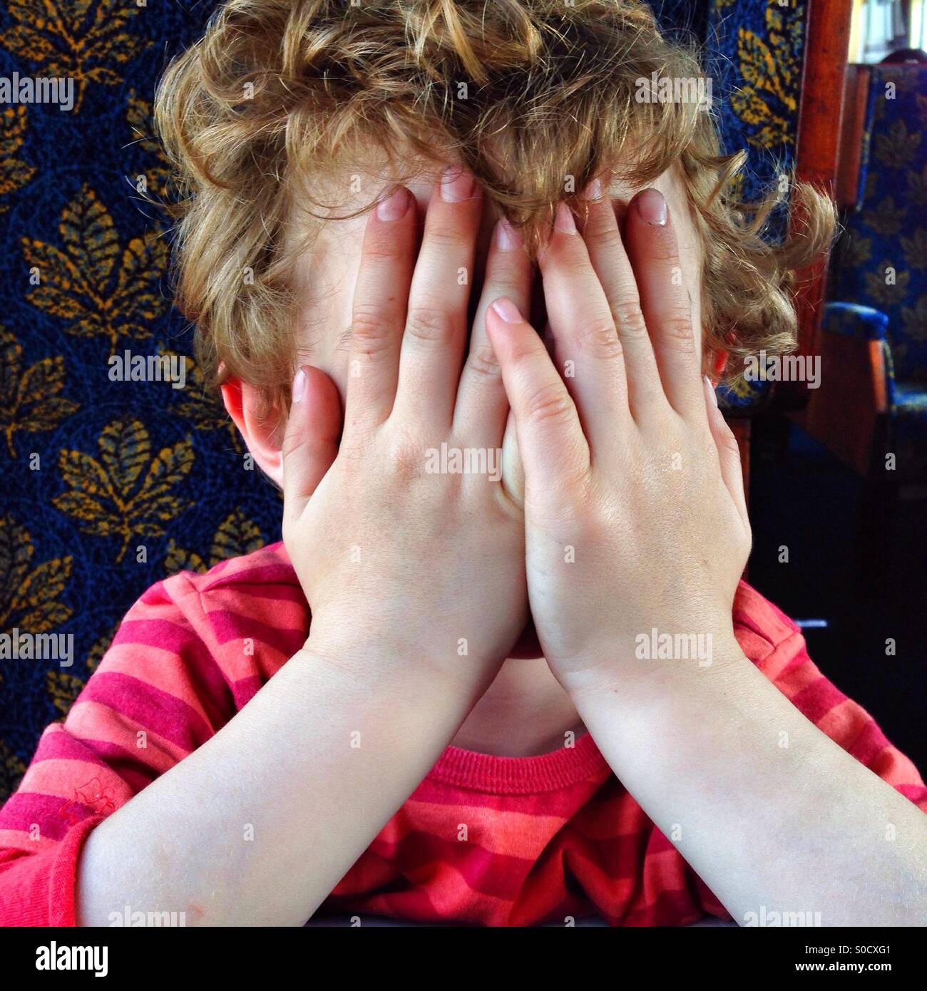Fünf Jahre alter Junge bedeckte sein Gesicht mit den Händen - Smartphone-aufgenommenes Stockfoto